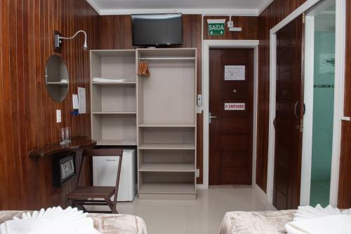 a room with two beds and a tv on the wall at Dalmo Hotel in Gravatal
