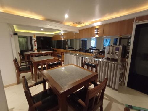 a dining room with tables and chairs and a kitchen at Dalmo Hotel in Gravatal