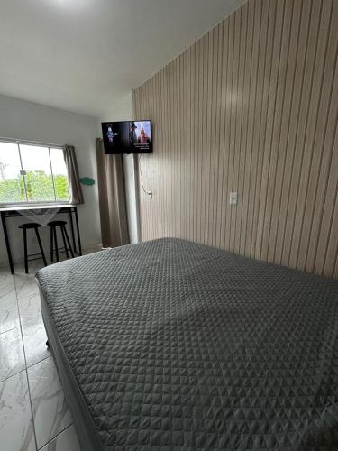 a bedroom with a bed and a tv on the wall at Pousada Mahalo in Palhoça