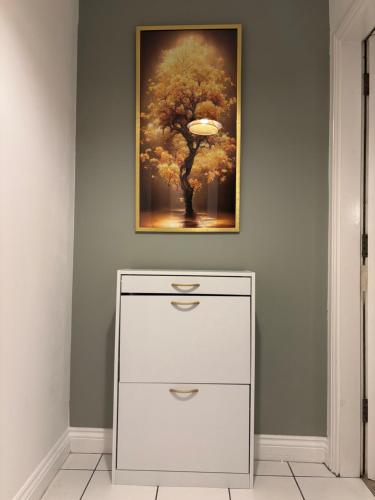 a painting of a tree on a wall with a dresser at 1 Bed Luxury Apartment in Nottingham