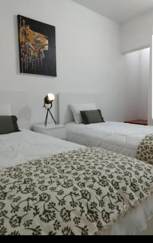 a bedroom with two beds with a black and white blanket at Casa do Raimundo in Évora
