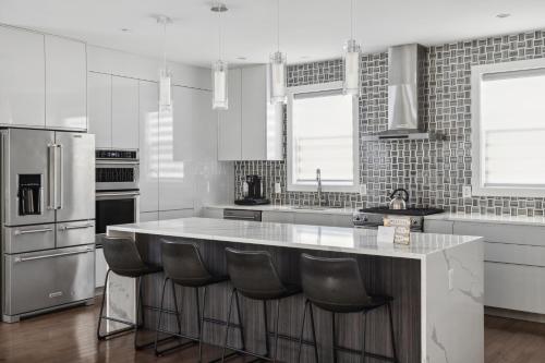 a white kitchen with a large island with bar stools at Luxury 4BR home 7 mins to US Capital, Rooftop deck, in Washington Free Parking in Washington, D.C.
