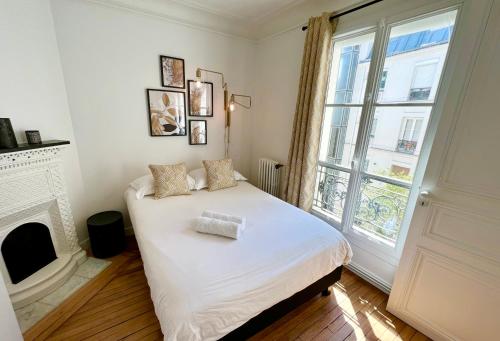 - une chambre avec un lit, une cheminée et une fenêtre dans l'établissement Appartement de charme - Place Victor Hugo - Paris 16e, à Paris