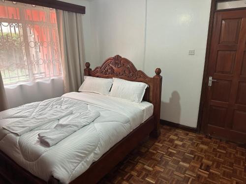 a bed with a wooden headboard in a bedroom at Milimani Guesthouse in Kitengela 
