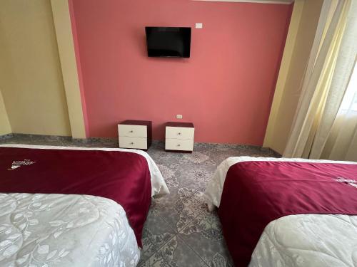 a room with two beds and a tv on the wall at HOTEL AREQUIPA in Nazca