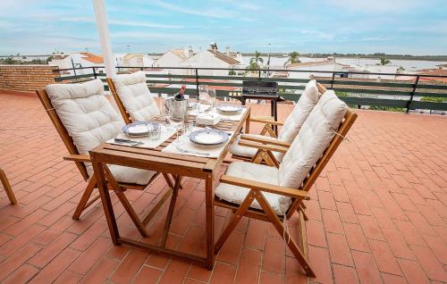 a wooden table with four chairs on a patio at Awesome Apartment In El Rompido in El Rompido