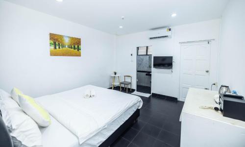 a white bedroom with a bed and a kitchen at Belle Cose Guest House Phuket in Patong Beach