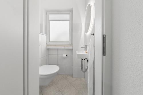 a white bathroom with a toilet and a window at VlNFUL2 Premium-Apartment mit Balkon und Parkplatz in Mülheim an der Ruhr