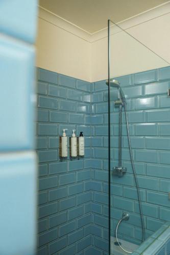 a bathroom with a blue tiled shower with a glass door at Hotel Boutique Casa Recreo in Viña del Mar