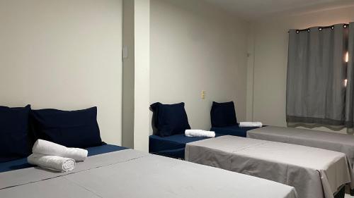 a room with two beds and two blue chairs at Pousada Conviver in Juazeiro do Norte