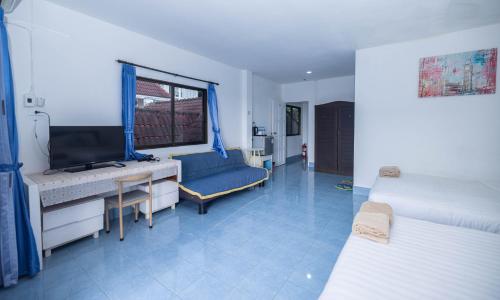 a room with two beds and a desk and a television at Belle Cose Guest House Phuket in Patong Beach