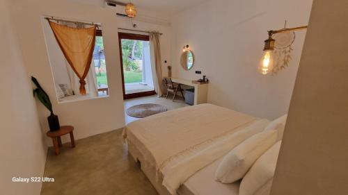 a bedroom with a bed and a desk and a window at Charleston's Ahangama in Ahangama