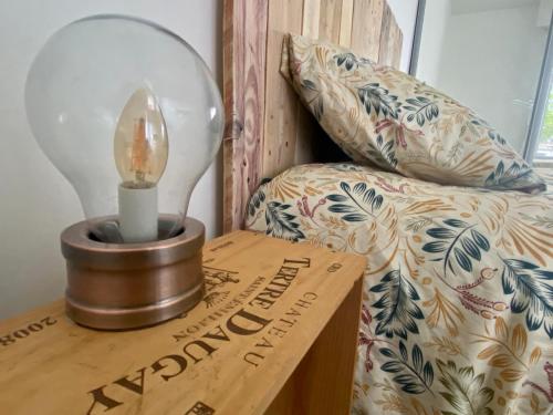 a lamp on a wooden table next to a bed at La parenthèse à Bordeaux - Pellegrin et Magistrature in Talence