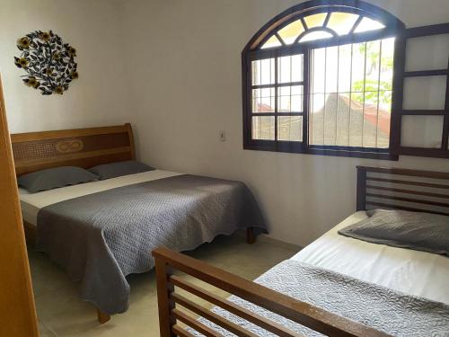 a bedroom with two beds and a window at Casa por do Sol amarelo in Araruama