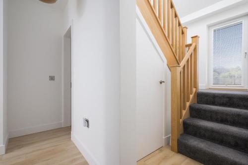 a staircase in a home with white walls and wood floors at Almara- Cosy cottage in fife in Fife