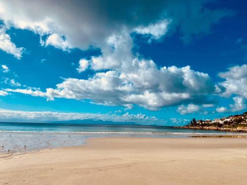 a beach with a cloudy sky and the ocean at Beach Front Retreat in Fish Hoek in Fish hoek