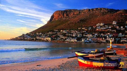 a beach with two boats on the beach with a mountain at Beach Front Retreat in Fish Hoek in Fish hoek