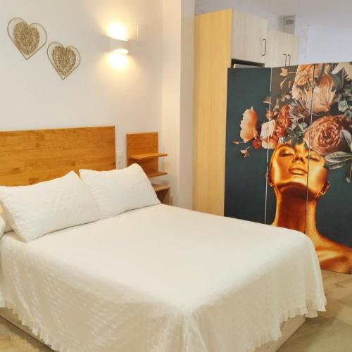 a bedroom with a bed and a painting of a woman at APARTAMENTO SOL in Chipiona