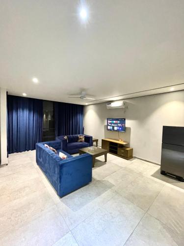 a living room with a blue couch and a flat screen tv at Sense luxury - 2 bed Apartment in Islamabad