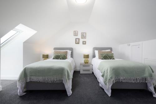 two beds in a room with white walls at Almara- Cosy cottage in fife in Fife