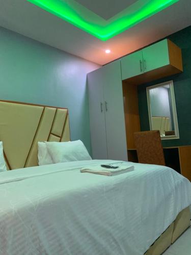 a bedroom with a white bed with a green light at Umbrella Properties hotels and apartments - Moniya in Ibadan