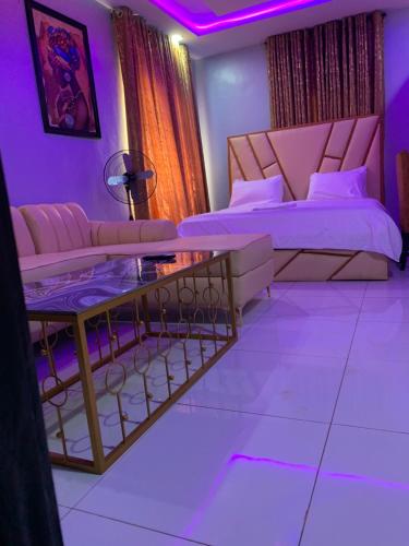 a bedroom with a bed and a couch and a table at Umbrella Properties hotels and apartments - Moniya in Ibadan