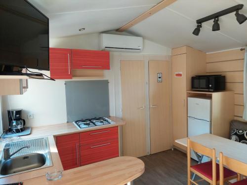 une petite cuisine avec des placards rouges et une table dans l'établissement Super Mercure, à Montaigu-Vendée