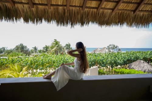 a woman sitting on a ledge looking out at the ocean at El Origen Villas & Spa-Puerto Escondido in Puerto Escondido