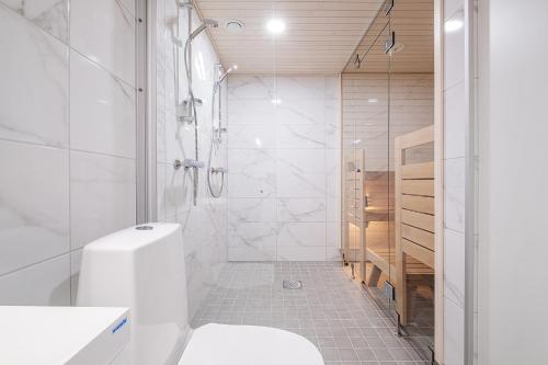 a white bathroom with a shower and a sink at Brand New 2BDR with Private Sauna in Rovaniemi