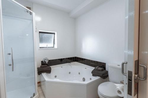 a white bathroom with a tub and a toilet at Palms Motel in Nelson