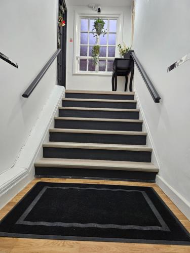 a stairway with a black rug and stairs with a window at Central Chambers Suites Suite 3 in Leek