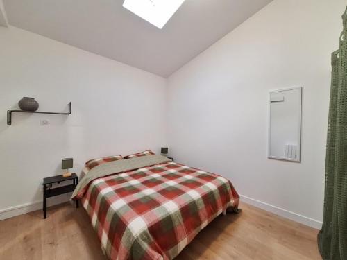 - une chambre blanche avec un lit et une couverture tressée dans l'établissement T2 Coeur de Ville - Casa Burot, à Rochefort