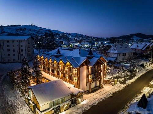 a large building with snow on the roof at night at Forest Green & Spa in Gura Humorului
