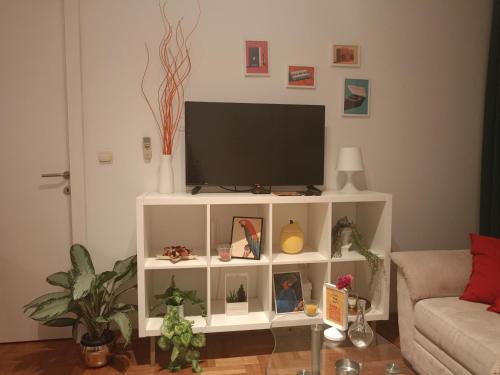 a living room with a tv on a white cabinet at Clockwork orange apartment in Vračar (historical)