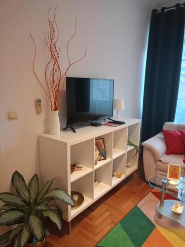 a living room with a tv on a white cabinet at Clockwork orange apartment in Vračar (historical)
