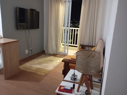 a living room with a table and a chair and a window at Apto em frente Beach Clube região privilegiada in Araraquara