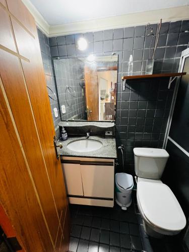 a bathroom with a sink and a toilet and a mirror at Apto no centro com 3 quartos in Ilhéus