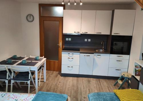 una cucina con armadi bianchi, tavolo e sedie di Apartment Misty Forest a Kranjska Gora