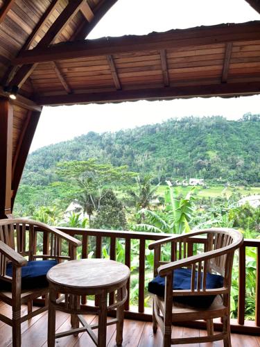 a room with two tables and chairs on a balcony at Lumbung Kembar Sidemen in Sidemen