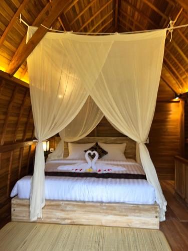 a bed in a room with a canopy at Lumbung Kembar Sidemen in Sidemen