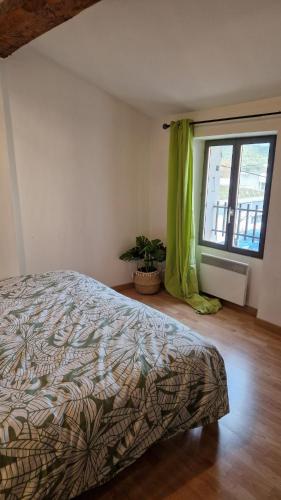 - une chambre avec un lit et une fenêtre avec une plante dans l'établissement Maison de village cosy Céret, à Reynès