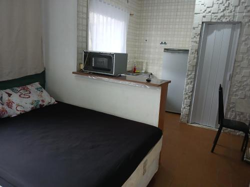 Una pequeña habitación con una cama y un microondas. en Recanto, en Mongaguá