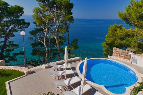 a swimming pool with chairs and the ocean at Villa Paulina in Brela