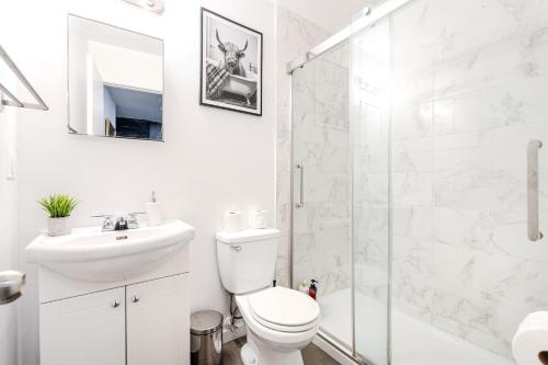 a bathroom with a toilet and a sink and a shower at Cozy 2-Bedroom in Griffintown in Montréal