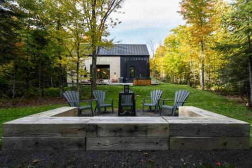 a house with chairs and a table in the yard at Villa Boreale - Wellness and relaxation in Petite-Rivière-Saint-François