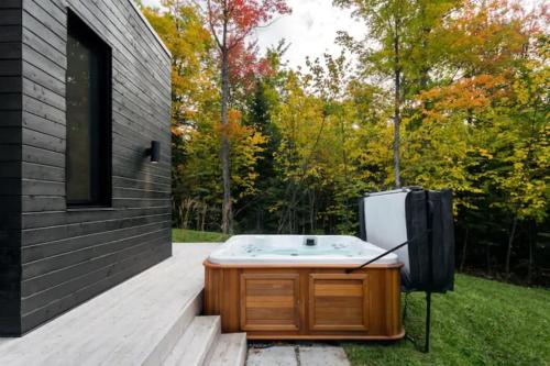 a bath tub sitting on a deck next to a house at Villa Boreale - Wellness and relaxation in Petite-Rivière-Saint-François