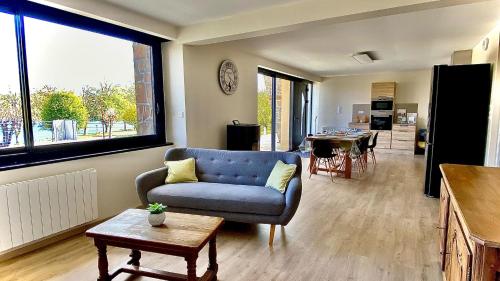 a living room with a blue couch and a table at Villa le Menhir 4 Ch au Bord du Lac et Terrasse in Villefranche-de-Panat