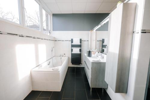 a bathroom with two sinks and a tub and a mirror at Le LOFT de la Route des Vins in Guebwiller