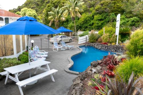 patio con sedie, ombrellone e piscina di Marlin Court Motel a Paihia