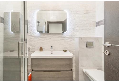 une salle de bain blanche avec un lavabo et un miroir dans l'établissement Nice promenade des anglais vue mer, à Nice